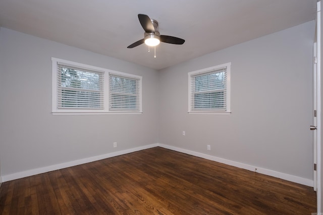 spare room featuring a ceiling fan, dark wood finished floors, and baseboards