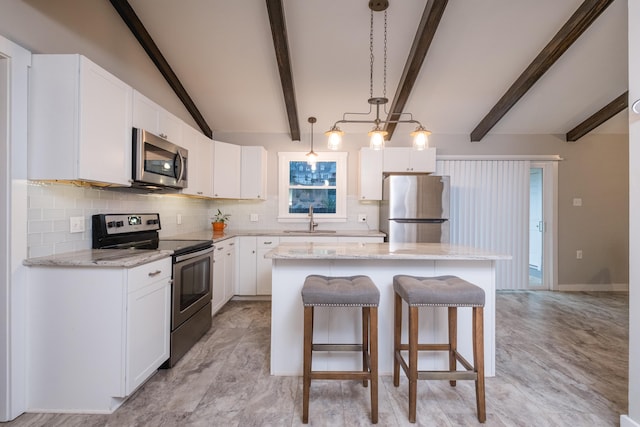 kitchen with a center island, stainless steel appliances, white cabinetry, pendant lighting, and a sink