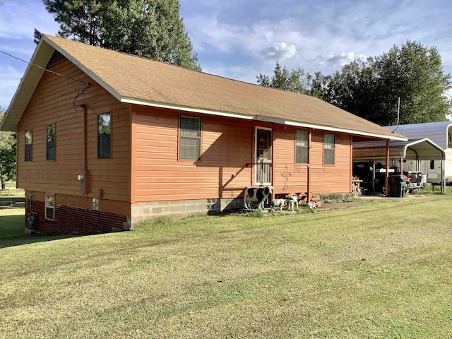 back of property featuring a lawn, a detached carport, and a shingled roof