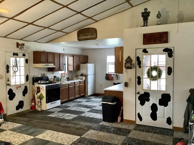 kitchen featuring vaulted ceiling, gas range oven, freestanding refrigerator, and light countertops