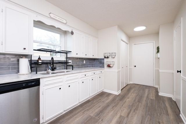 kitchen with a sink, white cabinetry, light countertops, and dishwasher