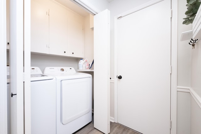 laundry room with light wood-style floors, washer and dryer, and cabinet space