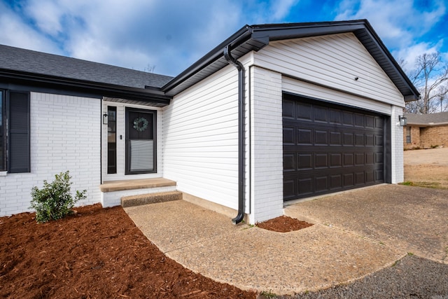 doorway to property with a garage, driveway, and brick siding