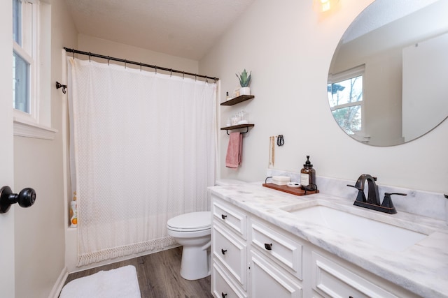 bathroom with toilet, wood finished floors, shower / bathtub combination with curtain, a textured ceiling, and vanity