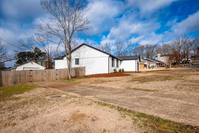 view of property exterior with a yard, fence, and a residential view