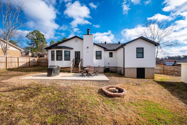 rear view of property featuring entry steps, an outdoor fire pit, a fenced backyard, a chimney, and a patio area