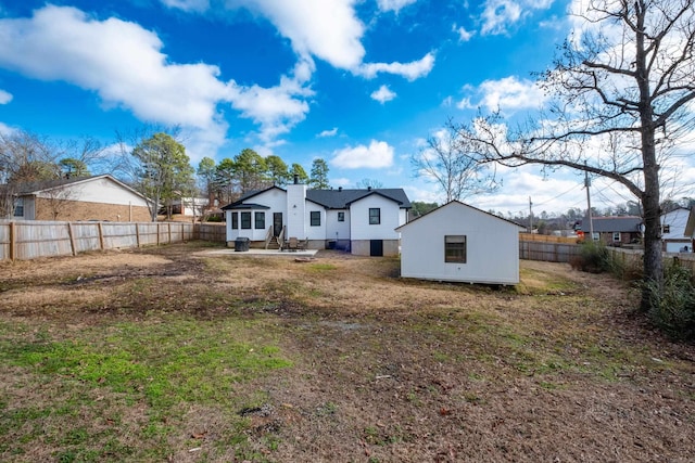 rear view of property featuring a fenced backyard and a lawn