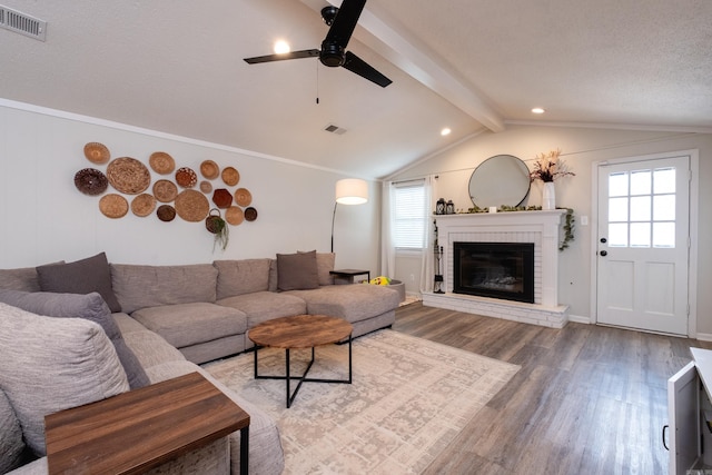 living room with vaulted ceiling with beams, a fireplace, wood finished floors, and visible vents