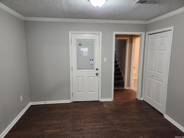 empty room featuring dark wood-type flooring, ornamental molding, a textured ceiling, and baseboards