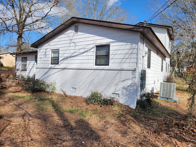 view of side of property featuring crawl space, central AC, and brick siding