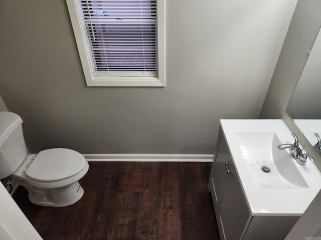 bathroom featuring toilet, vanity, baseboards, and wood finished floors