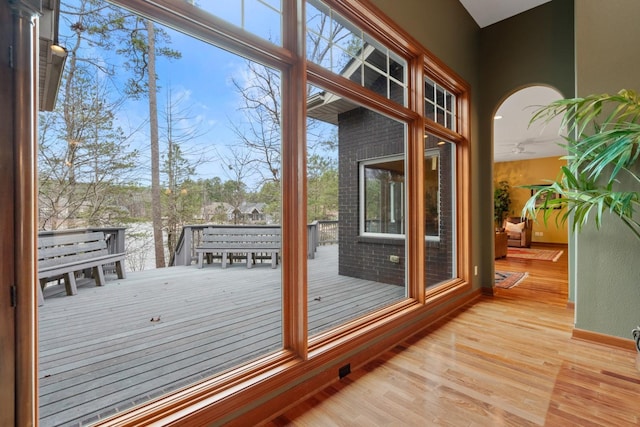 doorway to outside featuring light wood-style floors, arched walkways, and baseboards