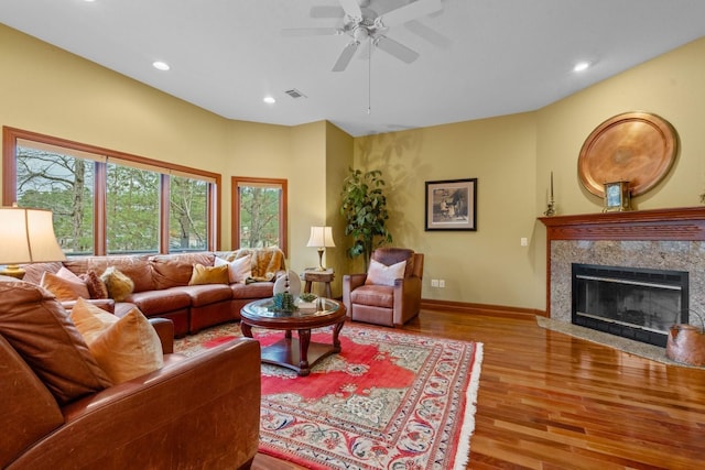 living room with light wood-style flooring, recessed lighting, visible vents, baseboards, and a high end fireplace