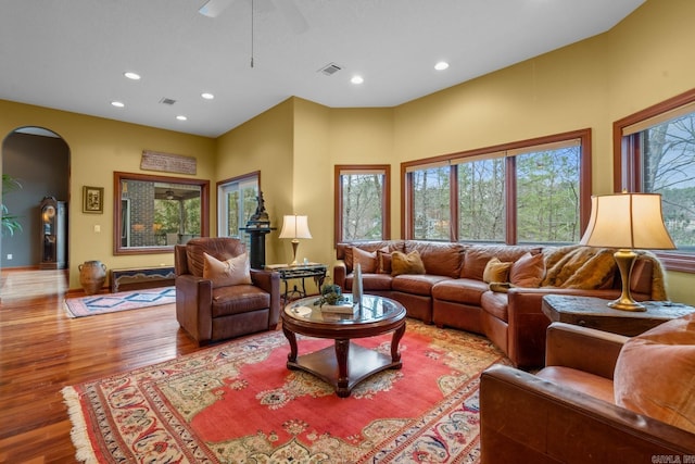 living area with light wood-type flooring, visible vents, arched walkways, and recessed lighting