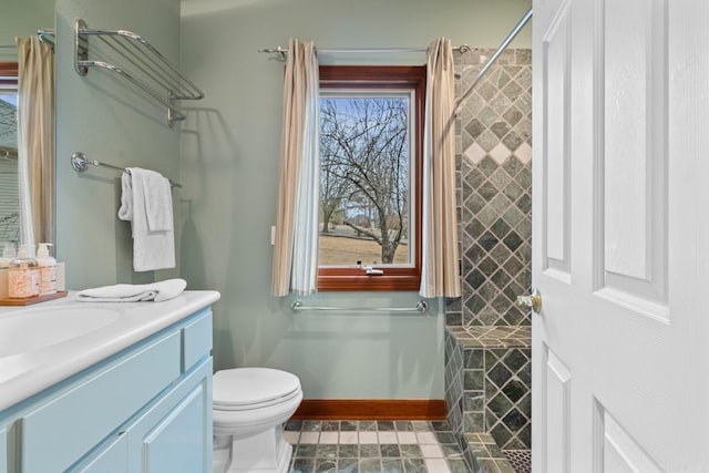 full bathroom featuring vanity, a tile shower, toilet, and baseboards