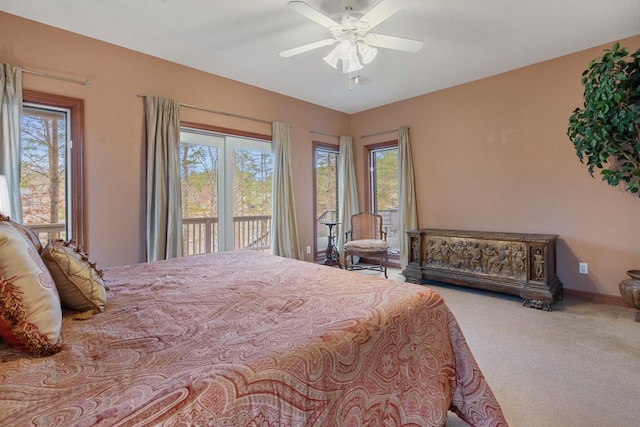 carpeted bedroom featuring baseboards, multiple windows, a ceiling fan, and access to exterior