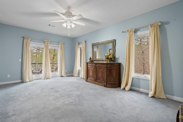 spare room featuring light carpet, plenty of natural light, a ceiling fan, and baseboards