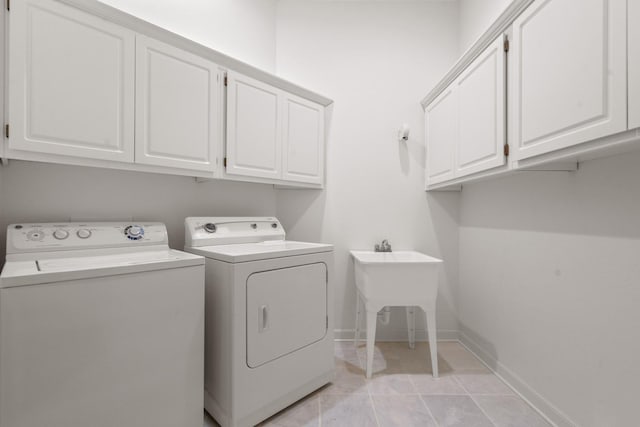 washroom with light tile patterned floors, a sink, baseboards, independent washer and dryer, and cabinet space