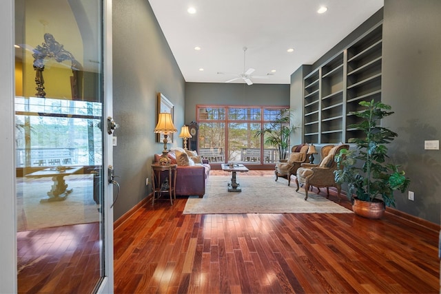 living area with a ceiling fan, baseboards, built in features, and wood finished floors
