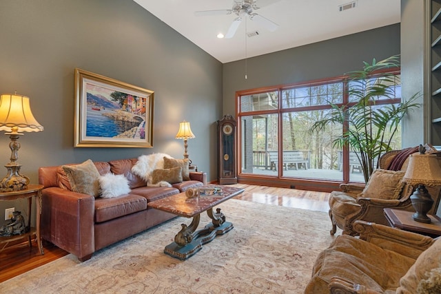 living room with visible vents, high vaulted ceiling, light wood-type flooring, and a ceiling fan