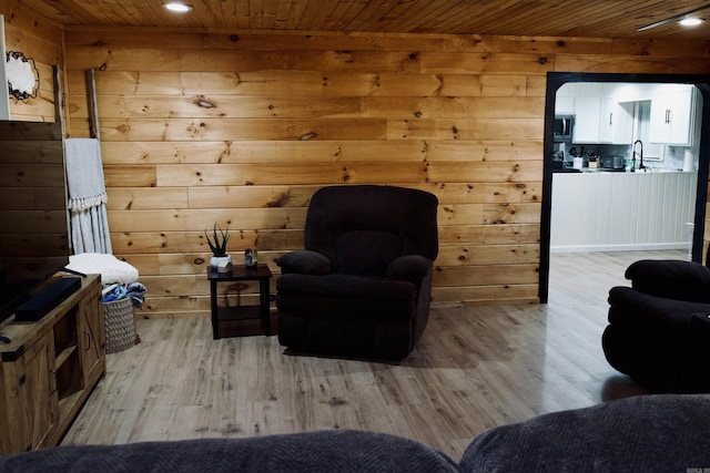 sitting room with light wood finished floors, wood walls, wooden ceiling, and recessed lighting