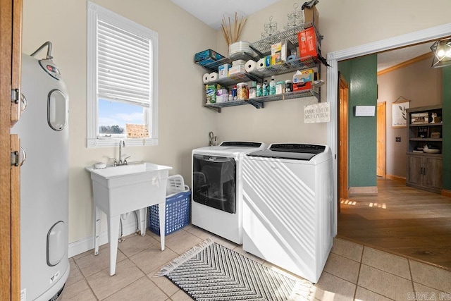 laundry room featuring light tile patterned floors, laundry area, baseboards, washing machine and dryer, and water heater