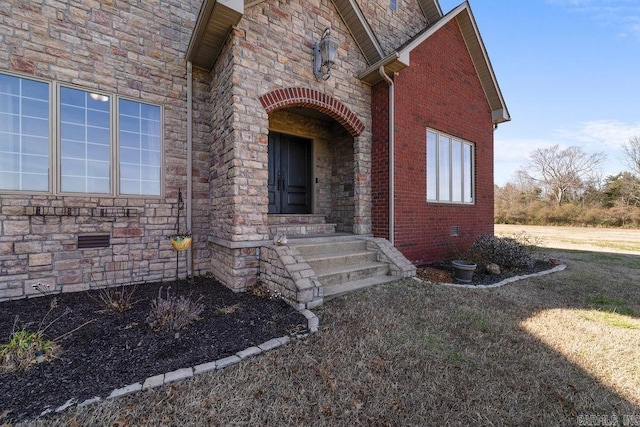 entrance to property featuring crawl space, stone siding, and brick siding
