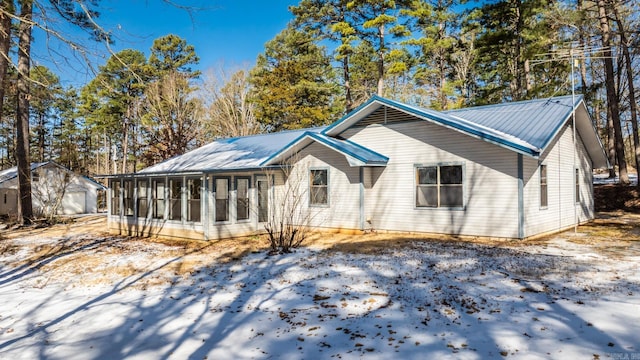 view of front of home featuring a sunroom, metal roof, and an outdoor structure