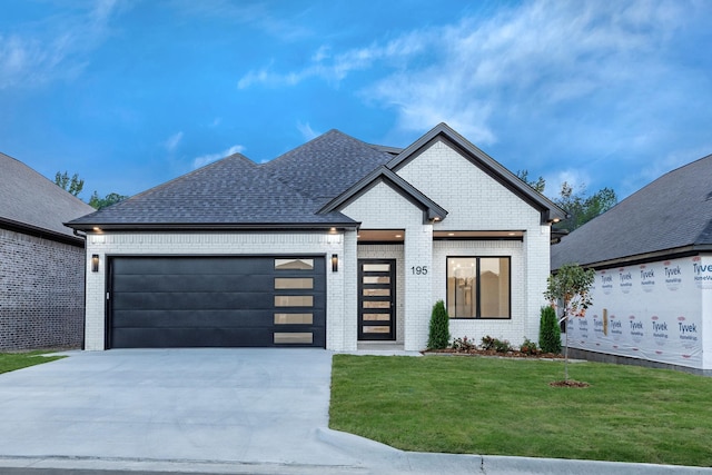 view of front of property with roof with shingles, a front lawn, concrete driveway, and brick siding