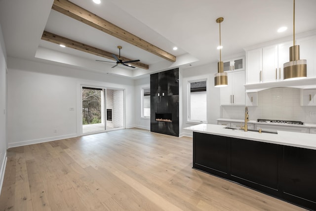 kitchen with white cabinets, open floor plan, hanging light fixtures, stainless steel gas cooktop, and a high end fireplace