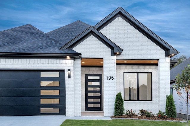 exterior space with a garage, driveway, a shingled roof, and brick siding