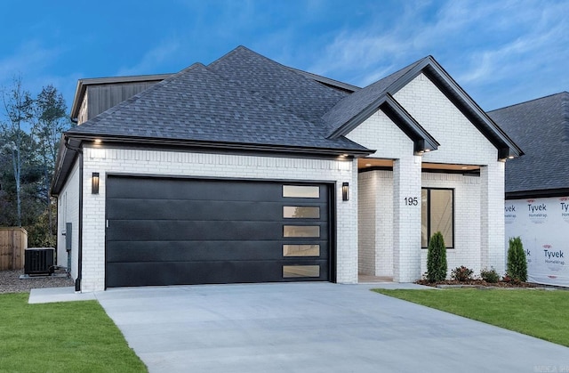 view of front facade with brick siding, a shingled roof, an attached garage, central AC unit, and driveway