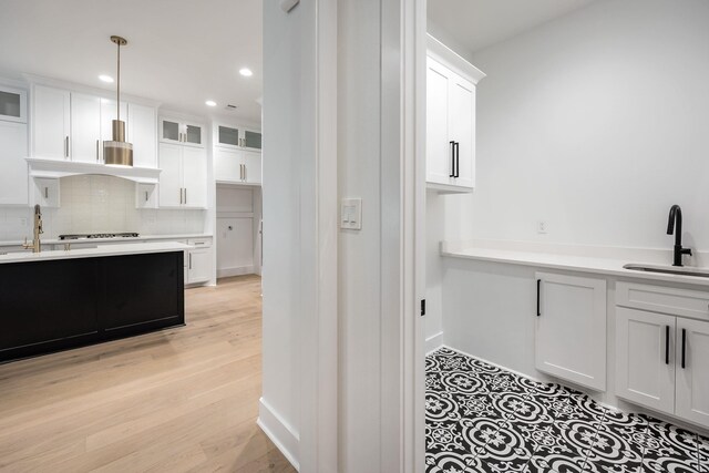 kitchen with white cabinets, glass insert cabinets, decorative light fixtures, light countertops, and a sink