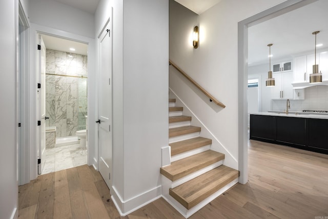 stairs with baseboards, wood finished floors, and recessed lighting