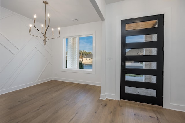 foyer with an inviting chandelier, wood finished floors, visible vents, and baseboards