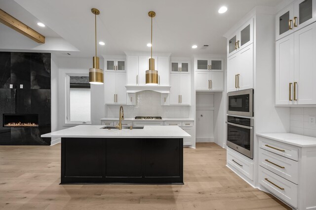 kitchen featuring appliances with stainless steel finishes, light countertops, a sink, and hanging light fixtures