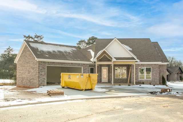 view of front of property featuring an attached garage, roof with shingles, concrete driveway, and brick siding