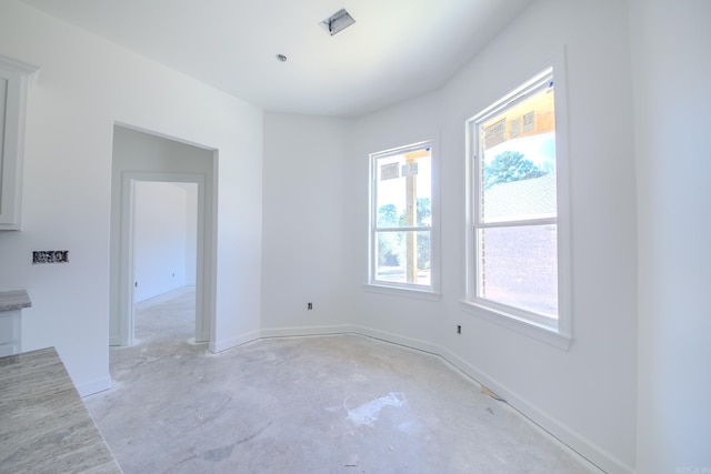 spare room featuring unfinished concrete flooring and baseboards