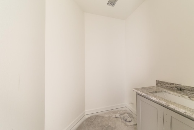 bathroom with concrete flooring, vanity, and baseboards