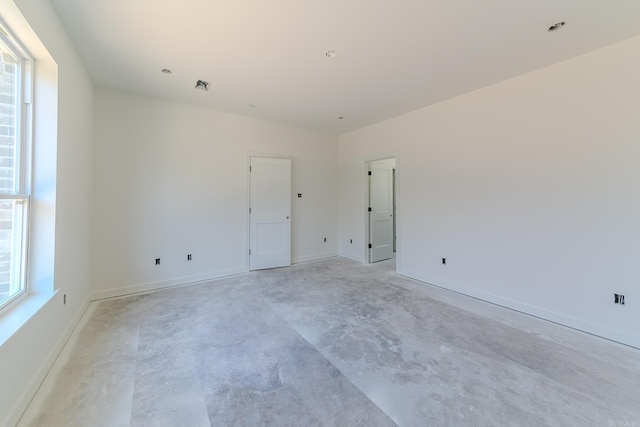 unfurnished room with baseboards, concrete flooring, and a wealth of natural light