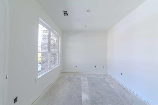 spare room featuring baseboards and concrete flooring