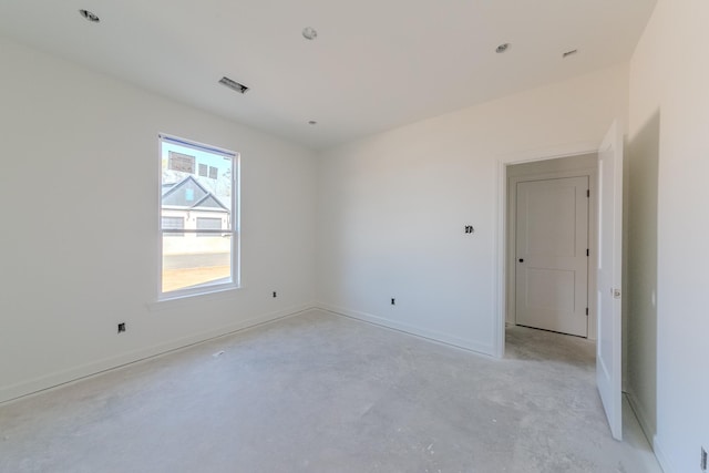 spare room featuring concrete flooring and baseboards