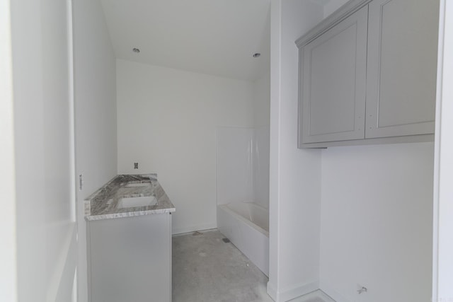 full bath featuring double vanity, baseboards, concrete floors, and a washtub