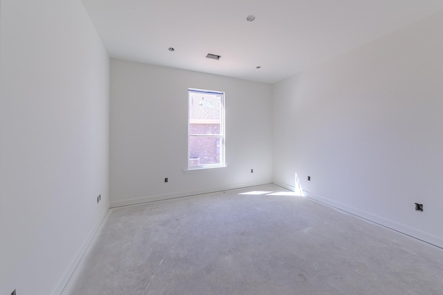 spare room featuring unfinished concrete flooring, visible vents, and baseboards