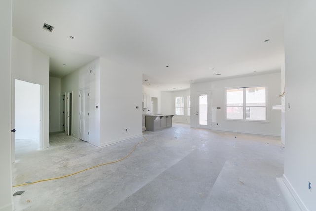 unfurnished living room featuring visible vents, baseboards, and unfinished concrete floors