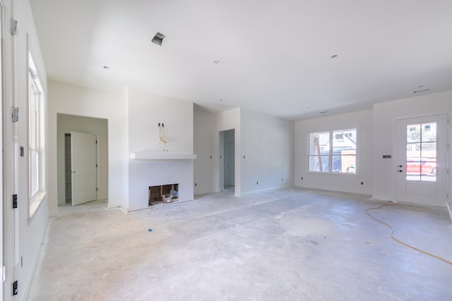 unfurnished living room featuring a fireplace, baseboards, and concrete flooring