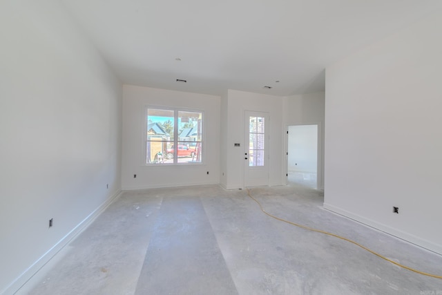 unfurnished room featuring concrete floors and baseboards