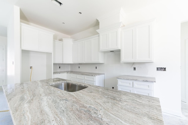 kitchen featuring white cabinetry, a center island with sink, and light stone countertops