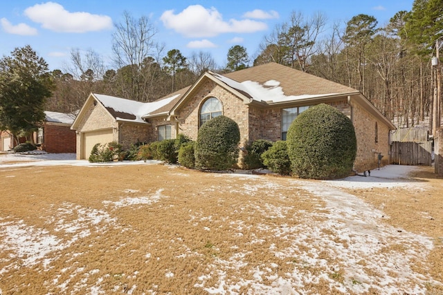 ranch-style house featuring brick siding, an attached garage, and fence