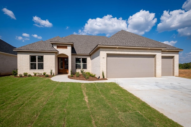 view of front of house featuring a garage, a front yard, driveway, and a shingled roof